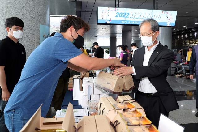 공단 본사 1층에서 ‘2022 사랑나눔 바자회’를 개최하고 있으며, 김한영 이사장이 물건을 구매하고 있다. 